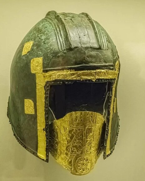  Bronze Funerary Helmet with gold foil mouthpiece depicting two heraldic lions to indicate the valor of the deceased hero from the necropolis at Archontiko, Greece 560-550 BCE. This helmet is from one of the earliest burials in the cemetery’s central